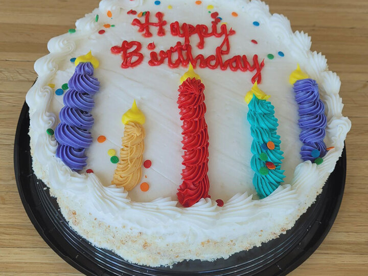 10 on. round vanilla cake with Happy Birthday written in frosting